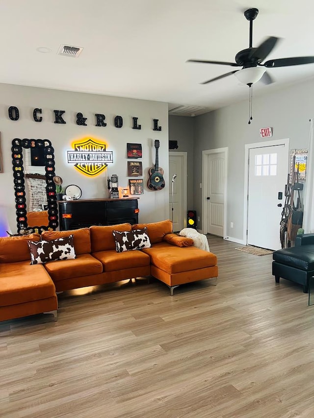 living room featuring light wood-style flooring, visible vents, a ceiling fan, and baseboards