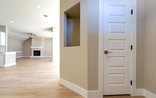 hall featuring lofted ceiling and light hardwood / wood-style floors