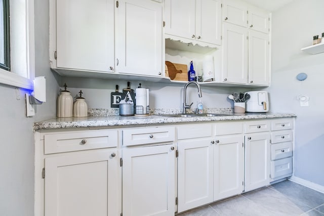 1632 Mission Ave, San Angelo, TX 76905 - kitchen with a sink, open shelves, white cabinets, light tile patterned flooring, and light stone counters