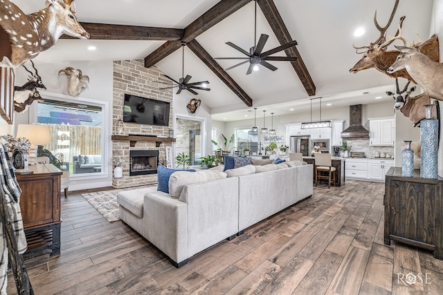 5949 Merrick St, San Angelo, TX 76904 - living area with a ceiling fan, a stone fireplace, beamed ceiling, dark wood-style flooring, and high vaulted ceiling