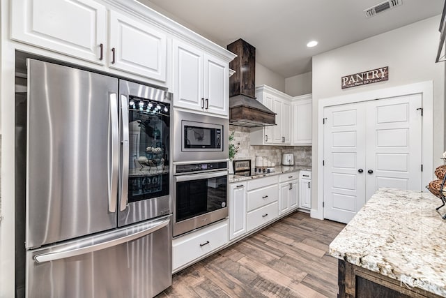 5949 Merrick St, San Angelo, TX 76904 - kitchen featuring stainless steel appliances, custom range hood, dark wood-type flooring, white cabinets, and decorative backsplash