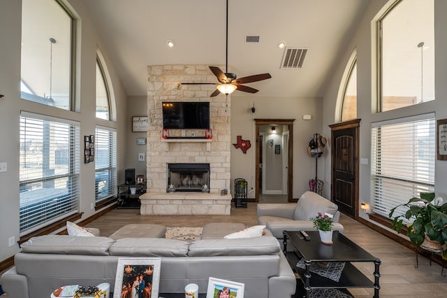 living room featuring high vaulted ceiling, visible vents, a fireplace, and wood finished floors