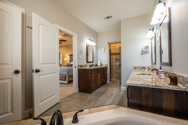 ensuite bathroom with visible vents, a stall shower, connected bathroom, vanity, and wood finished floors