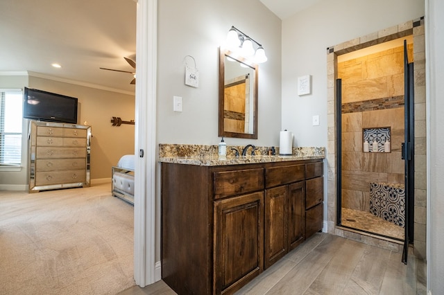 full bathroom featuring crown molding, a stall shower, ceiling fan, vanity, and baseboards