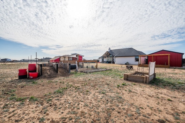 view of yard featuring an outbuilding, a vegetable garden, an outdoor structure, and fence