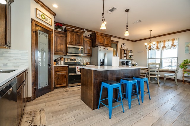 kitchen featuring a center island, visible vents, backsplash, appliances with stainless steel finishes, and a kitchen breakfast bar