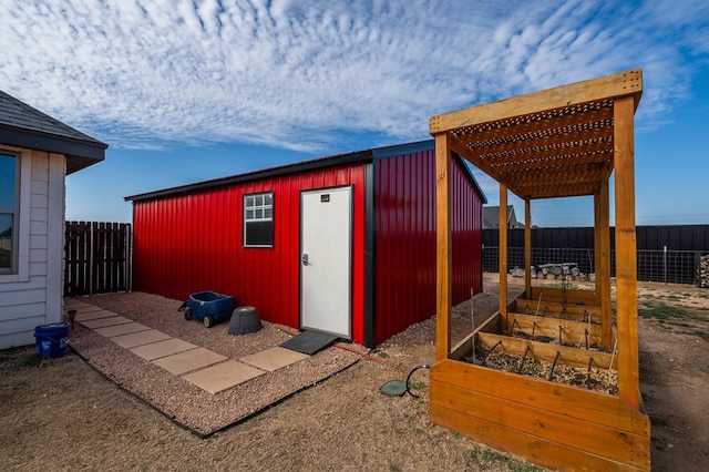 view of outbuilding with fence private yard, a garden, an outdoor structure, and a pergola