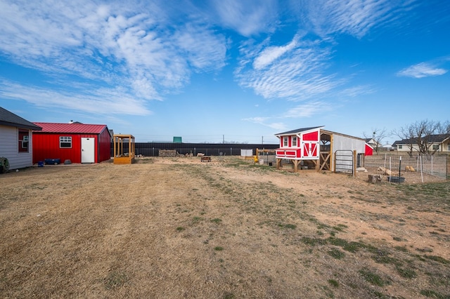 view of yard featuring an outbuilding, fence, and exterior structure