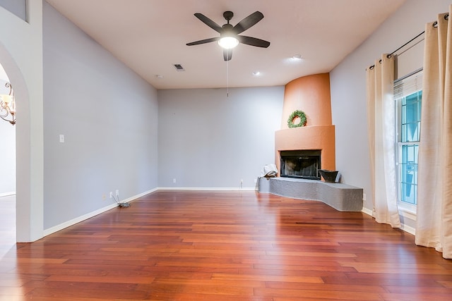 unfurnished living room with a healthy amount of sunlight, hardwood / wood-style floors, a large fireplace, and ceiling fan