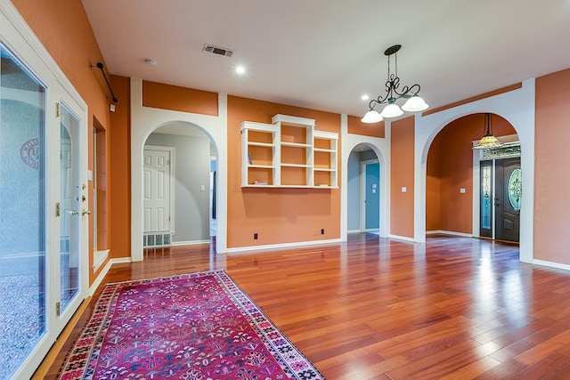 spare room with hardwood / wood-style floors and an inviting chandelier