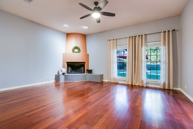 unfurnished living room with hardwood / wood-style flooring, a large fireplace, and ceiling fan