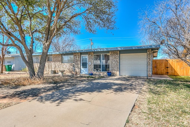 ranch-style home featuring stone siding, an attached garage, concrete driveway, and a gate