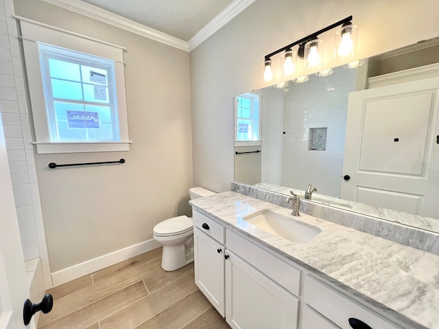 bathroom featuring toilet, wood finish floors, vanity, baseboards, and ornamental molding