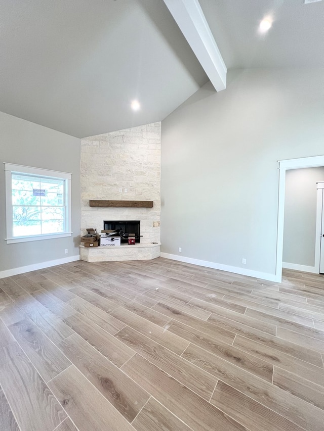 unfurnished living room with a fireplace, baseboards, beamed ceiling, and wood finish floors