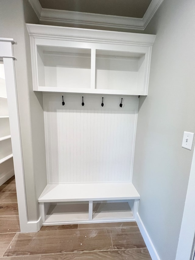 mudroom featuring crown molding, baseboards, and wood finished floors