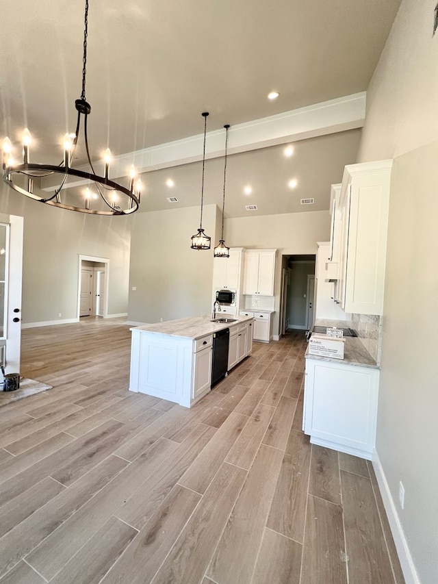 kitchen featuring dishwasher, open floor plan, hanging light fixtures, light countertops, and white cabinetry