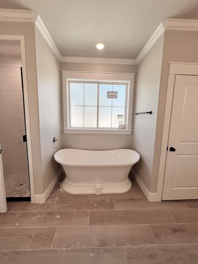 full bathroom with a soaking tub, baseboards, crown molding, and wood finish floors