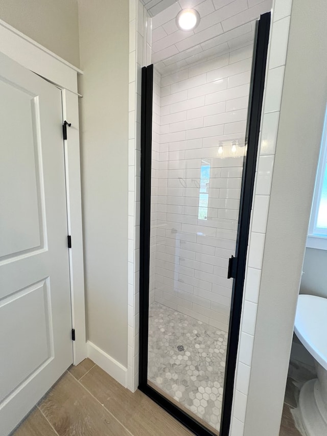 full bathroom with a shower stall and baseboards