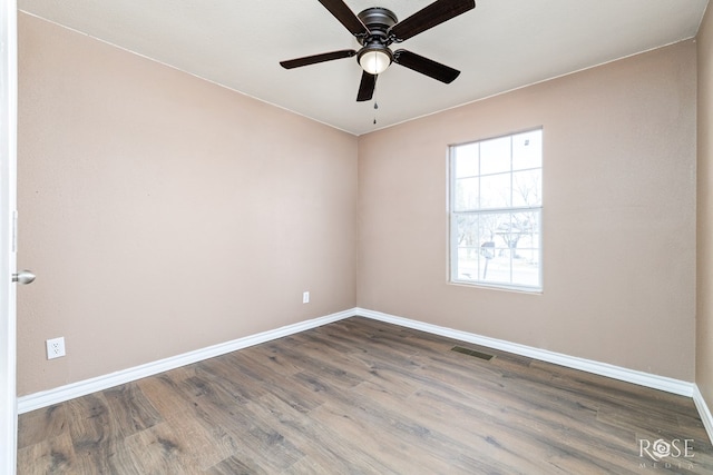 spare room featuring a ceiling fan, baseboards, visible vents, and wood finished floors