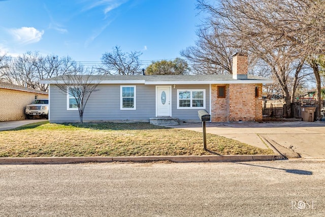 single story home with driveway, a chimney, fence, a front yard, and brick siding