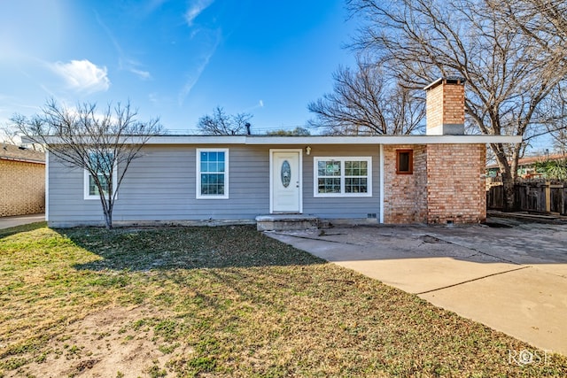 ranch-style home featuring brick siding, fence, a chimney, and a front lawn