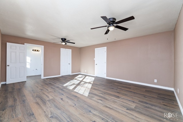 spare room with dark wood-type flooring, baseboards, and a ceiling fan