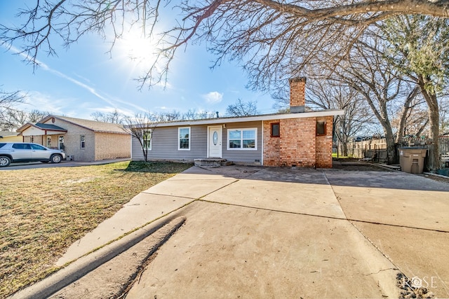 single story home with brick siding, a chimney, and a front yard