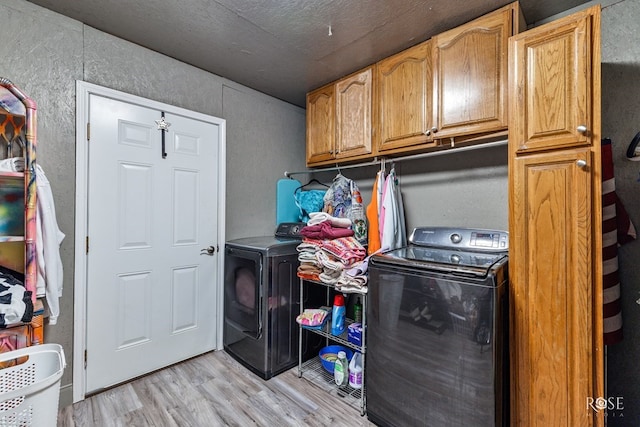 clothes washing area with cabinets, washing machine and clothes dryer, and light wood-type flooring