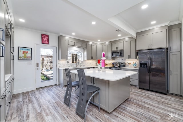 kitchen featuring sink, appliances with stainless steel finishes, a center island, light stone counters, and light hardwood / wood-style floors