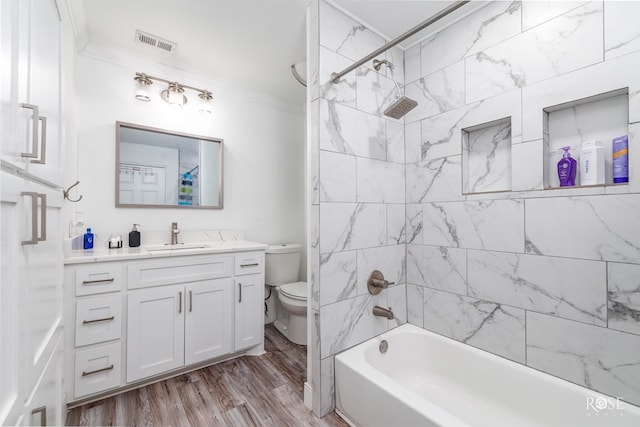 full bathroom with toilet, crown molding, vanity, tiled shower / bath combo, and hardwood / wood-style floors