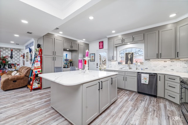 kitchen with gray cabinets, backsplash, light hardwood / wood-style floors, a kitchen island, and stainless steel dishwasher