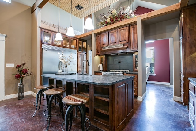 2030 Silver Creek Ct, San Angelo, TX 76904 - kitchen with finished concrete flooring, dark countertops, a sink, an island with sink, and baseboards