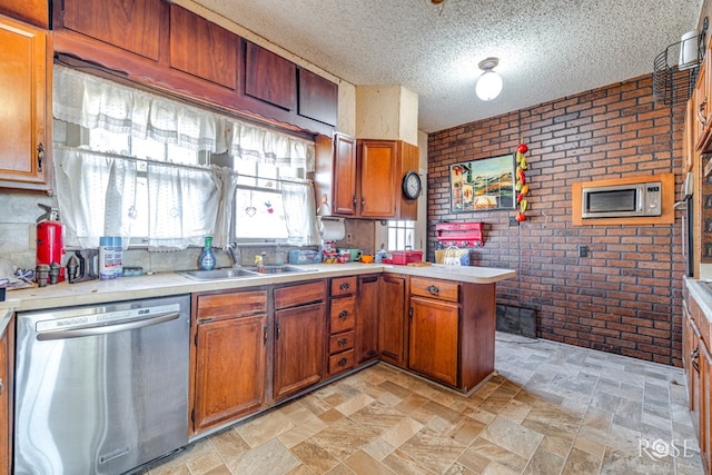 kitchen with sink, dishwasher, a textured ceiling, brick wall, and kitchen peninsula