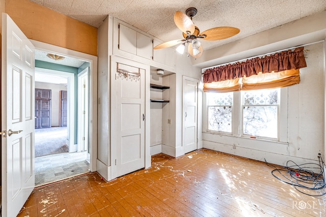 unfurnished bedroom featuring ceiling fan, hardwood / wood-style floors, a textured ceiling, and a closet