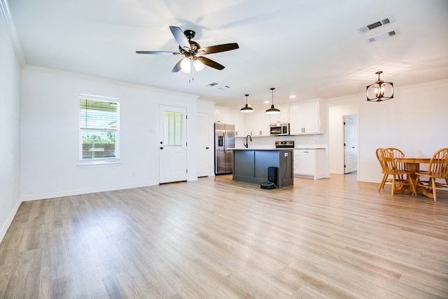 909 E 39th St, San Angelo, TX 76903 - living room featuring crown molding, light wood-style flooring, a ceiling fan, and a chandelier
