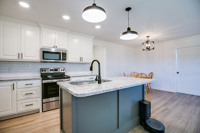 909 E 39th St, San Angelo, TX 76903 - kitchen featuring stainless steel appliances, light wood finished floors, decorative backsplash, white cabinets, and crown molding