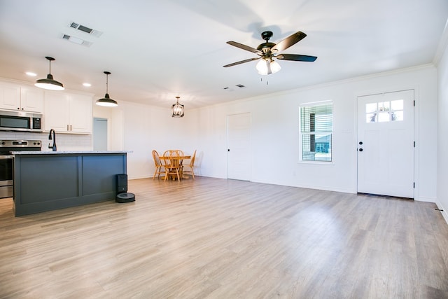 909 E 39th St, San Angelo, TX 76903 - kitchen featuring appliances with stainless steel finishes, crown molding, light wood finished floors, backsplash, and pendant lighting