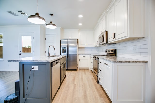 909 E 39th St, San Angelo, TX 76903 - kitchen featuring appliances with stainless steel finishes, light wood-style floors, white cabinets, ornamental molding, and tasteful backsplash