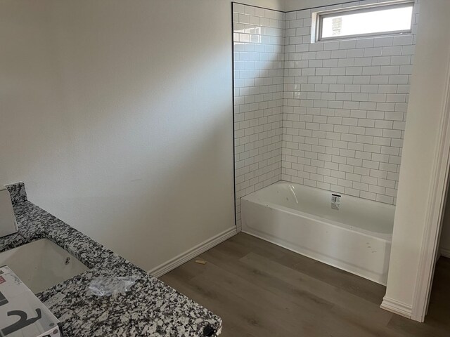 bathroom featuring hardwood / wood-style flooring, vanity, and tiled shower / bath combo