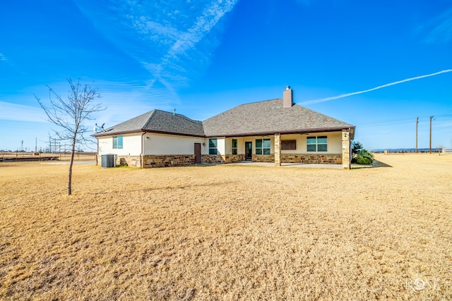 rear view of property with stucco siding, stone siding, central AC unit, and a chimney