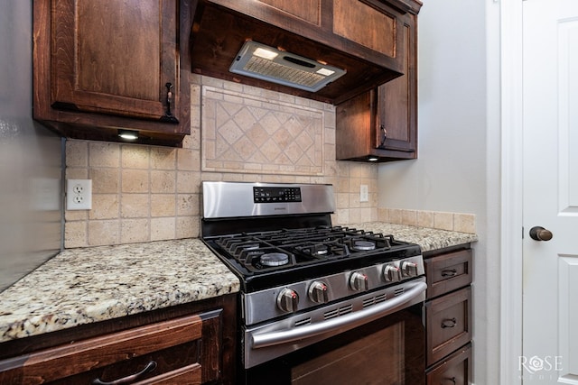 kitchen featuring stainless steel gas stove, dark brown cabinetry, tasteful backsplash, and light stone counters