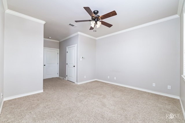 carpeted empty room featuring crown molding, baseboards, visible vents, and ceiling fan