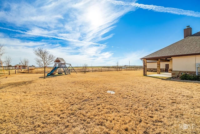 view of yard featuring a patio, fence, and a playground