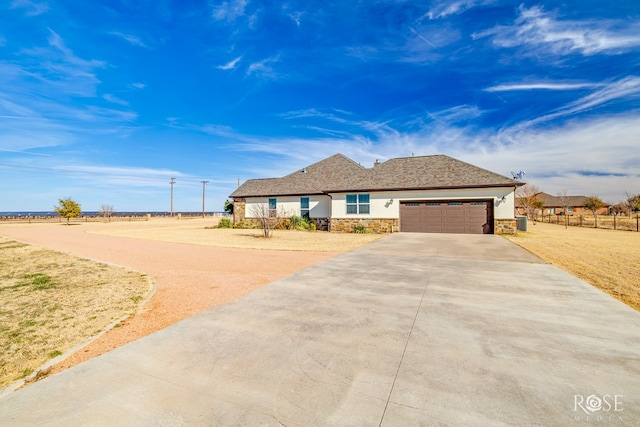 ranch-style house featuring stone siding, stucco siding, an attached garage, and driveway