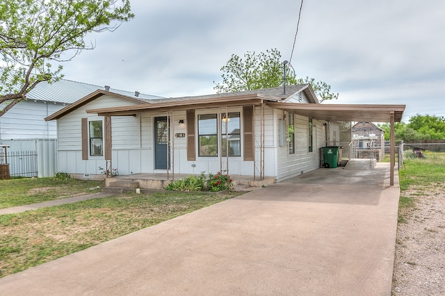 view of front of house with a front lawn, driveway, an attached carport, a porch, and fence