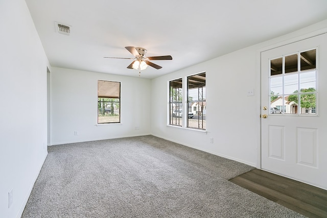 carpeted spare room with baseboards, visible vents, and ceiling fan
