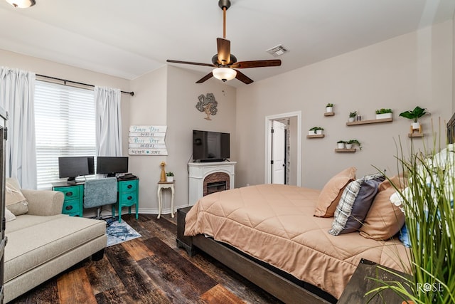 bedroom with visible vents, baseboards, a fireplace, dark wood-style floors, and a ceiling fan