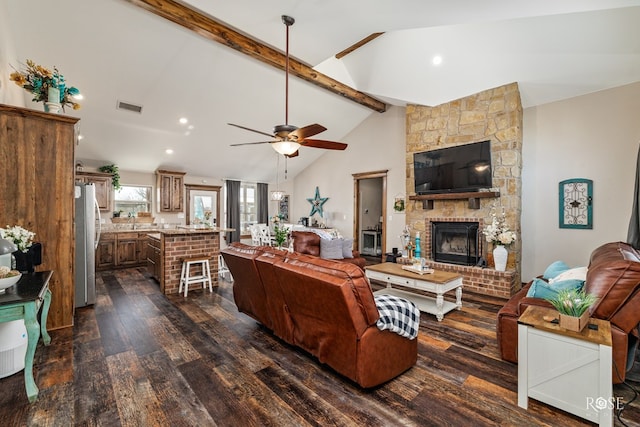 living room with visible vents, a ceiling fan, lofted ceiling with beams, dark wood finished floors, and a fireplace