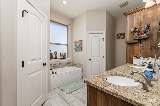 bathroom with a bath, visible vents, double vanity, and a sink