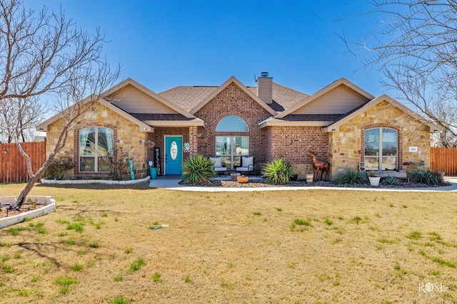 ranch-style home featuring brick siding, a front lawn, fence, a chimney, and stone siding